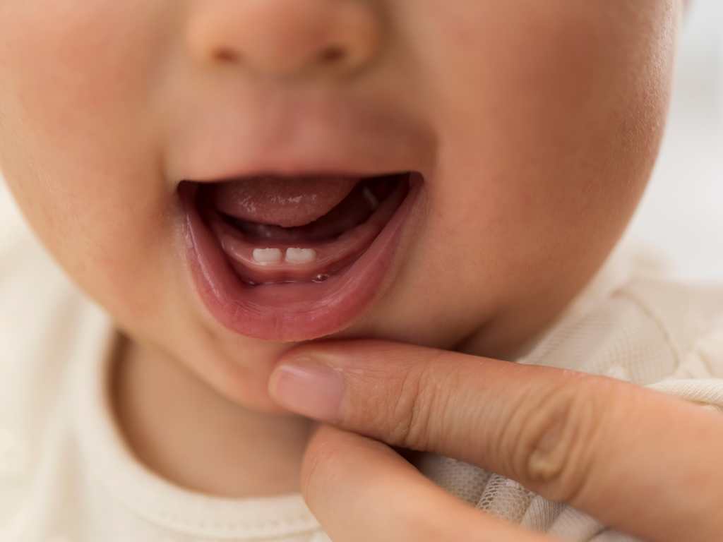 A close-up of a hand gently touching a baby's chin, with soft, natural lighting and a blurred background.